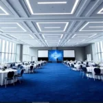 Modern Dubai banquet hall featuring a digital stage backdrop and a vibrant blue carpet.