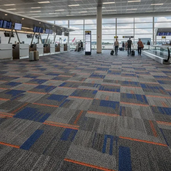 Modern airport terminal with patterned carpet, check-in counters, and travelers walking toward large runway windows.