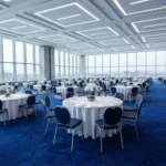 Modern banquet hall in Dubai with round tables and a vibrant blue patterned carpet.