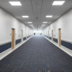 modern building corridor in Dubai featuring blue patterned carpet and bright overhead LED lights.