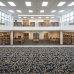 spacious library atrium featuring a decorative floral carpet and bright overhead lighting.
